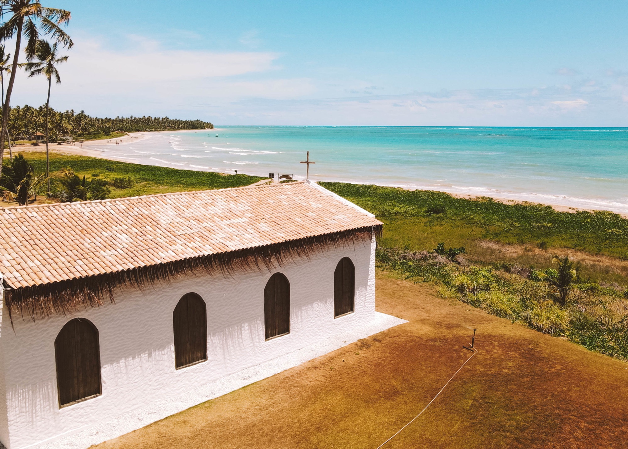 Capela dos Milagres à beira-mar, entre coqueiros e águas turquesa